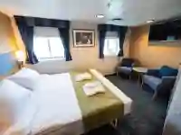 The superior double cabins (4) are spacious with a double bed, separate sitting area with two armchairs, cabinets, one large wardrobe, TV, and a private bathroom with shower and toilet. – Norwegian Adventure Company