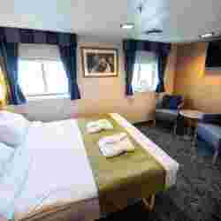 The superior double cabins (4) are spacious with a double bed, separate sitting area with two armchairs, cabinets, one large wardrobe, TV, and a private bathroom with shower and toilet. – Norwegian Adventure Company